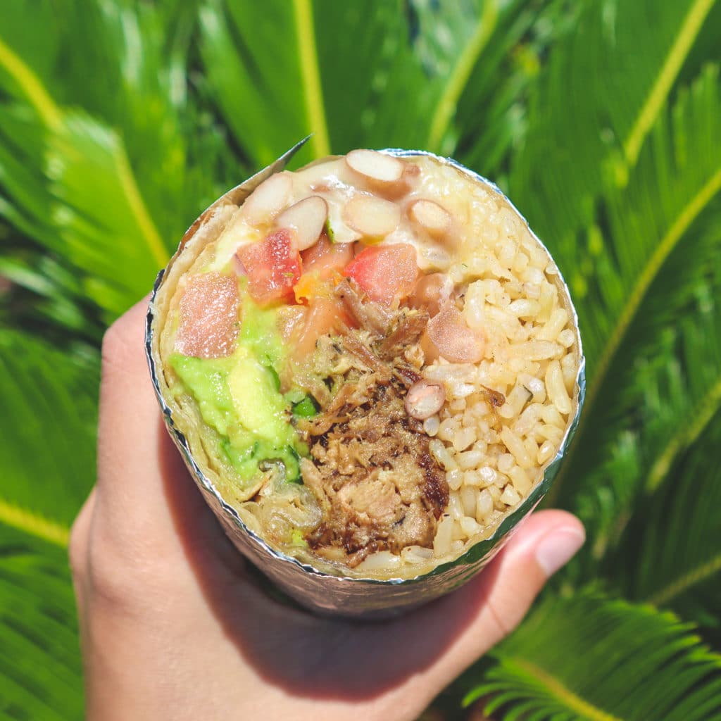 Poppos' burrito in front of palm leaves, cross-cut to show off the healthier, natural ingredients