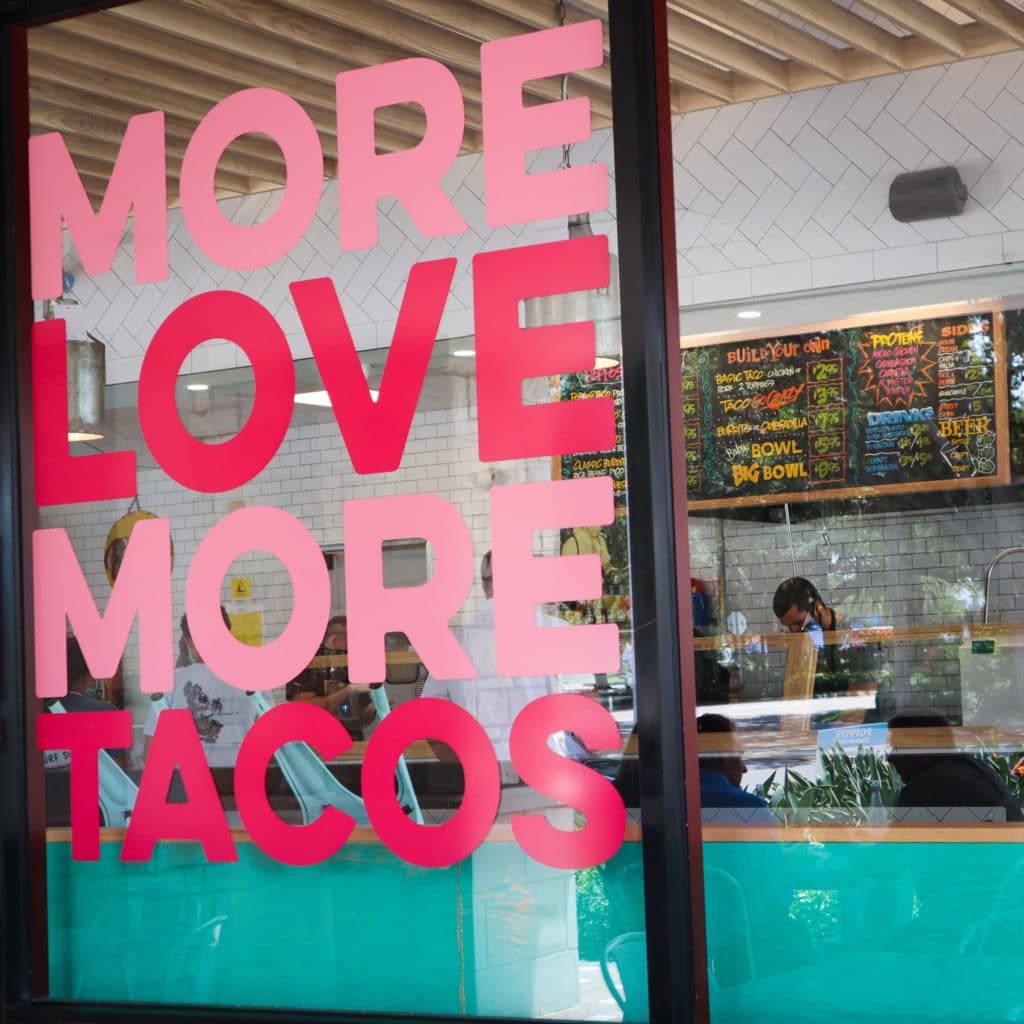 Window sign reading "More Love More Tacos"